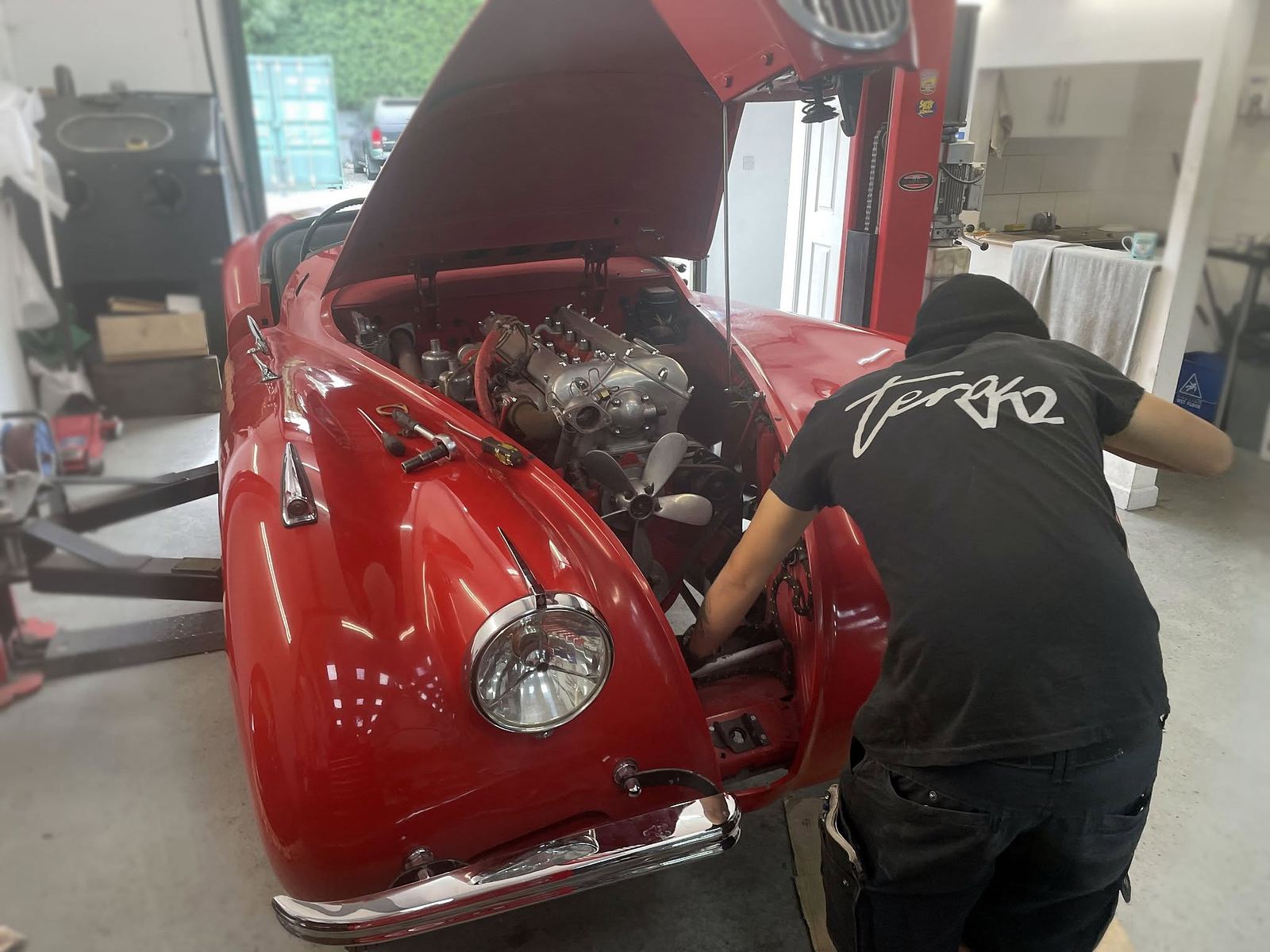 A technician working on a classic car V8 engine