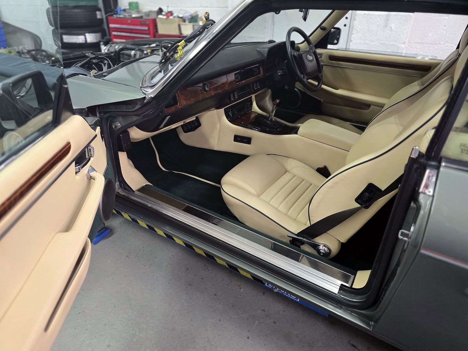 A classic car interior with tan leather and wood dash being detailed