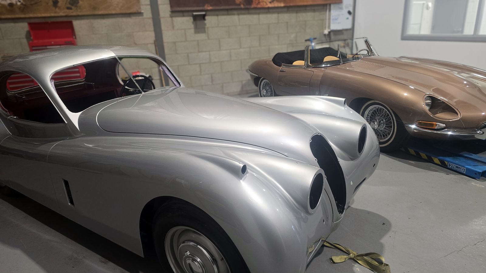 The XK120 Coupé parked in the workshop alongside a bronze E-Type convertible