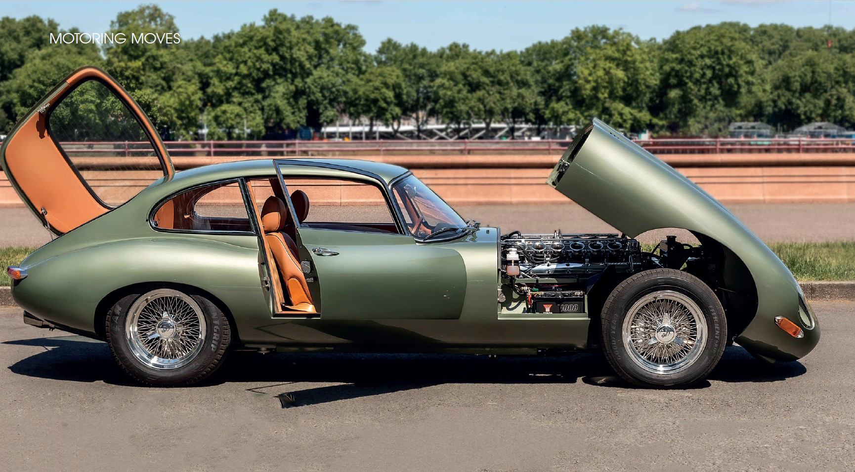 Sage green E-Type coupe with bonnet, driver's door and rear hatch open — MOTORING MOVES feature
